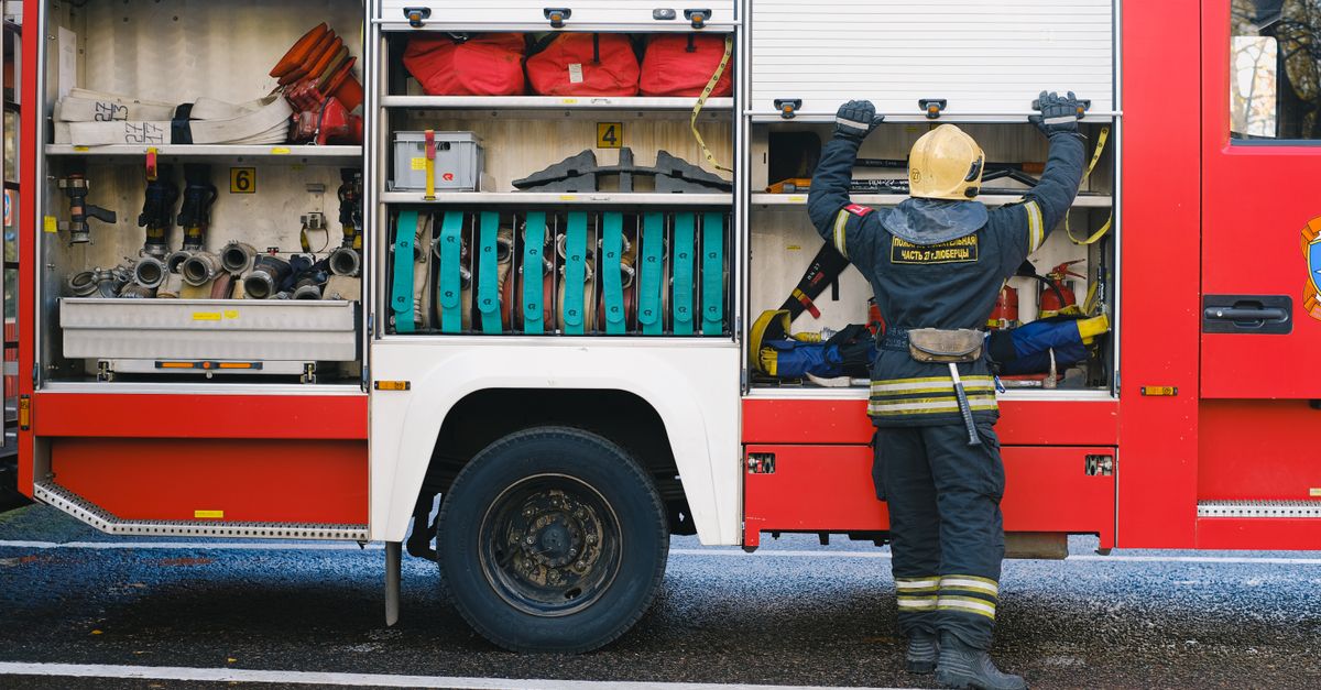 A dedicated firefighter organizing essential equipment on the side of a fire truck.
